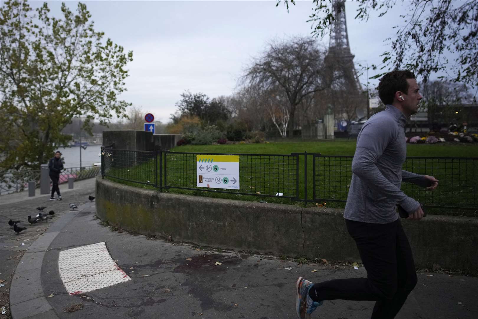 A man jogs past a blood stain at the site where a man targeted passers-by (Christophe Ena/AP)