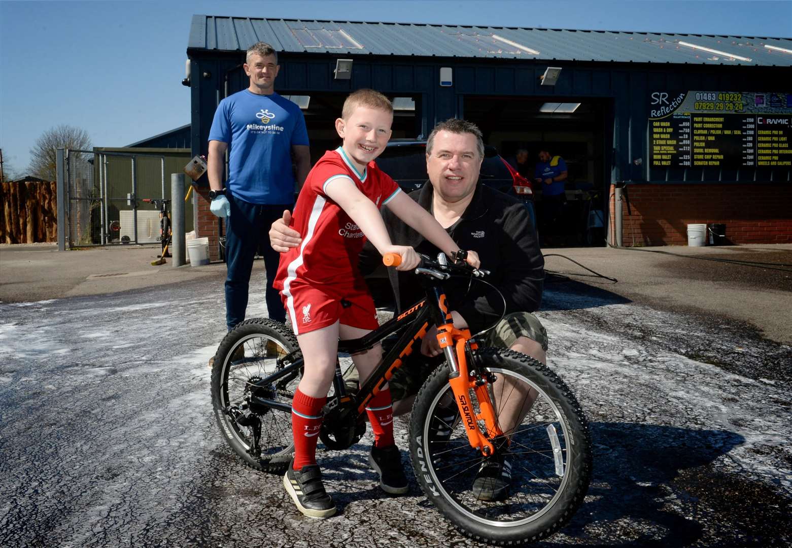 SR Reflection charity car wash..Robert Murray, owner of SR Reflection presenting one of the bikes to Archie Maclean, who raised Â£65 for Mikeysline by cycling 60 miles on his old bike, with his dad, Angus Maclean..Picture: James Mackenzie..
